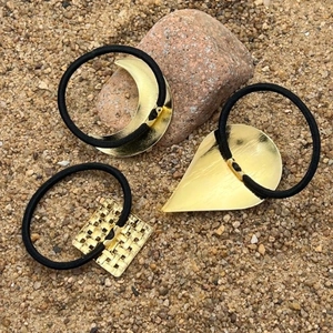 Three-piece gold metal hair ties with moon and droplet shapes on black elastic bands
