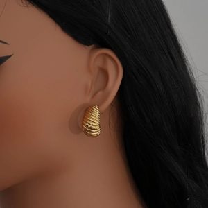 Detailed close-up of a model wearing golden spiral twist chunky hoop earrings for women