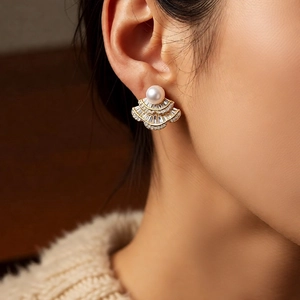 Close-up of a vintage fan-shaped zircon pearl earring worn by a model on the ear