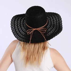 Detail of black lace sun hat with hollowed texture and brown ribbon bow decoration