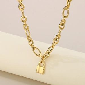Macro shot of gold oval link chain necklace featuring a polished metal lock pendant