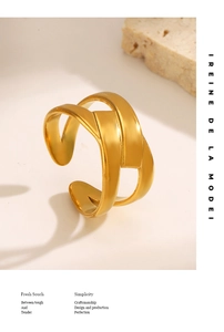 Close-up of gold layered criss-cross ring on a white surface with beige stone
