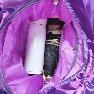 Interior view showing the large capacity of the purple tote with a bottle and umbrella