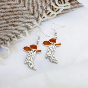 Detail view of silver cowboy boot and hat earrings with orange enamel and zircon studs
