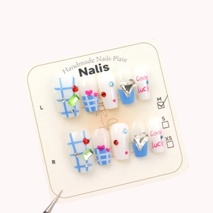 Blue plaid press-on nails with heart charms and Good Luck text on a white display card