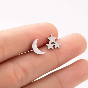 Detail shot of silver crescent moon and star stud earrings held to show relative size