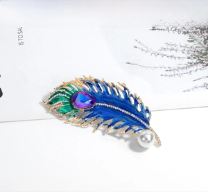 Detailed peacock feather brooch with blue enamel, sparkling rhinestones and a pearl accent