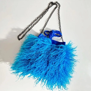 Close-up of blue faux sheep fur bucket bag with black metal chain and leather drawstring
