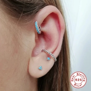 Macro shot of S925 sterling silver ear cuff set with turquoise stones on model's ear