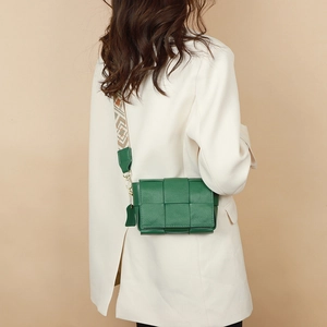 Detail of green woven leather crossbody bag with a patterned wide fabric shoulder strap