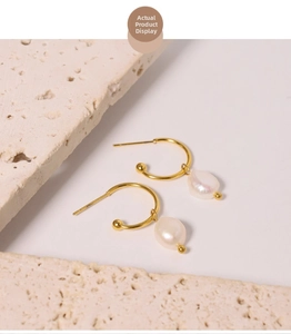 Detailed view of C-shaped gold earrings featuring natural white Baroque pearls