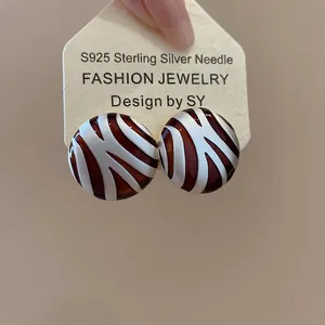 Detail of geometric round stud earring with brown zebra pattern and S925 silver needle