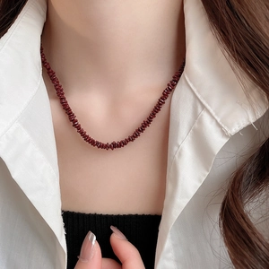 Close-up of deep red irregular stone beaded necklace on a white shirt background