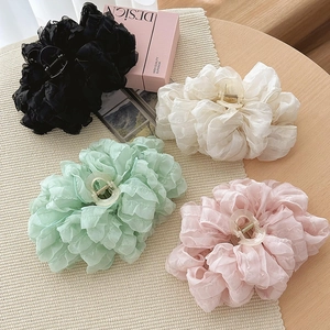 Large chiffon flower hair claws in multiple colors shown on a neutral textured background