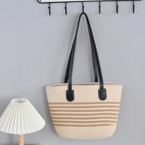 Detail view of woven tote bag with brown stripes and long black leather shoulder straps