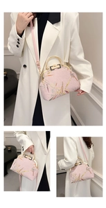 Detail of pink embroidered handbag featuring traditional bird motifs and gold metal handle