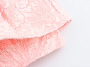 Dettaglio macro del tessuto rosa con fiori a rilievo e bordo con cucitura rifinita