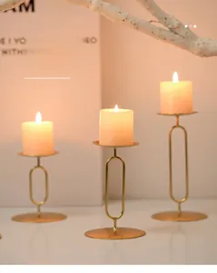 Three gold Nordic iron candle holders in varying heights with round bases and sleek oval frames