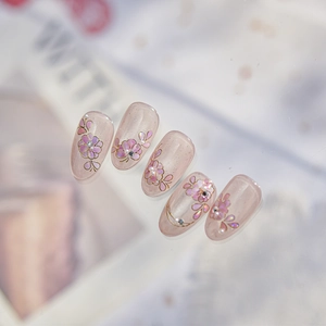 Close-up of pink press-on nails with 3D floral art, gold accents and pearls