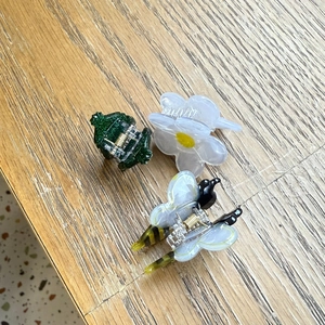 Close-up of cute acrylic hair clips with frog, daisy, and bee designs on wooden surface