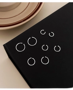 Collection of seven minimalist S999 sterling silver hoop earrings on a black display stand