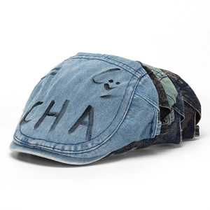 Detailed view of stacked vintage washed denim flat caps with graffiti smile graphics