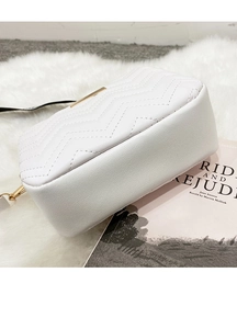 Close-up of white V-quilted leather bag with golden metallic lock on plush carpet