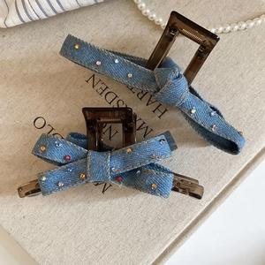 Detailed close-up of blue denim bow hair claws with colorful sparkling rhinestones