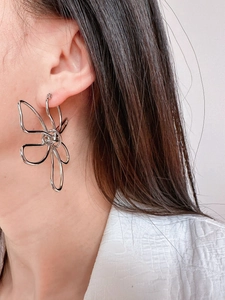 Close-up of a model wearing large silver hollow metal butterfly earrings in a modern style