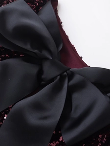 Detail of burgundy sequin fabric with a black ribbed bow on this elegant dress