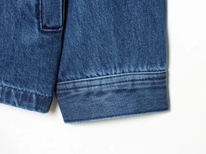 Dettaglio macro del polsino di una giacca di jeans blu scuro con cuciture rifinite