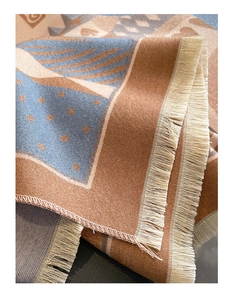 Detailed view of scarf featuring geometric patterns, brown-blue color block and beige tassels