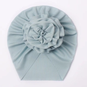 Detail of baby turban hat featuring light blue pleated knit fabric and a large floral accent