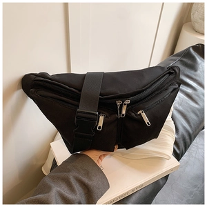 Detail of black nylon crossbody bag featuring multiple silver zippers and wide shoulder strap