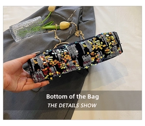 Detailed bottom view of black sequin evening bag with gold chain on grey fabric