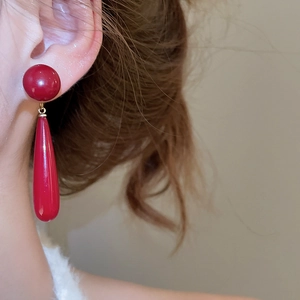 Detail showing the deep red teardrop pendant earrings with 18k gold plating on model