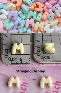Macro detail of mixed macaron color letter M resin beads for DIY jewelry with size scale