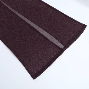 Dettaglio del tessuto in maglia bordeaux scintillante con spacco alto sul vestito