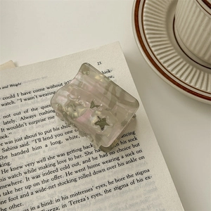 Close-up of a translucent grey star-patterned hair claw clip on an open book page