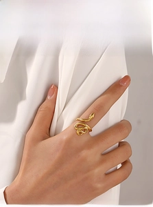 Détail d'une bague serpent dorée polie montrant le design enveloppant sur un doigt