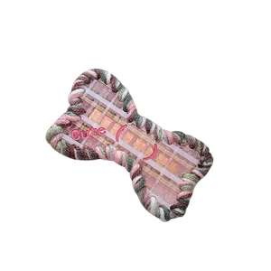 Cute bone-shaped hair clip with knitted edges and pink embroidery on white background