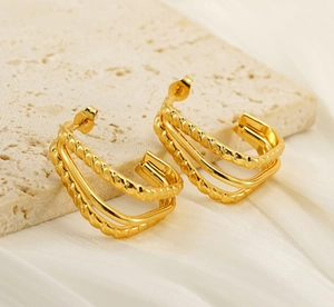 Close-up of triple-layered gold stainless steel hoop earrings with twisted texture details