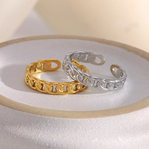 Close-up of minimalist gold and silver chain link open rings on a white ceramic tray