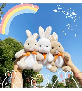 Close-up of white and brown plush bunny toys with carrot ties held against a blue sky
