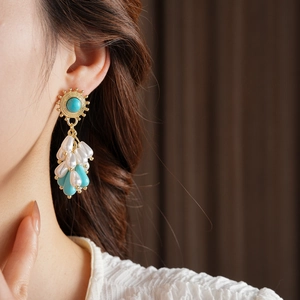 Macro view of vintage turquoise earrings with white pearl tassels on a model