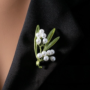 Detail of green leaf brooch with white pearls pinned on a professional black blazer lapel