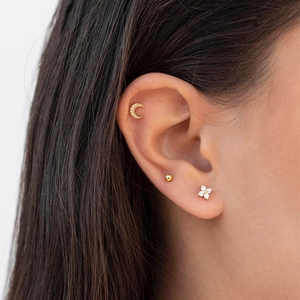 Detailed view of model wearing gold flower studs and crescent moon earring set