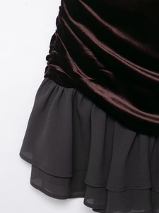 Détail d'une robe en velours avec plis marrons et ourlet volanté en mousseline noire