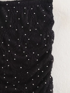 Détail du tissu plissé noir avec strass argentés scintillants et texture raffinée