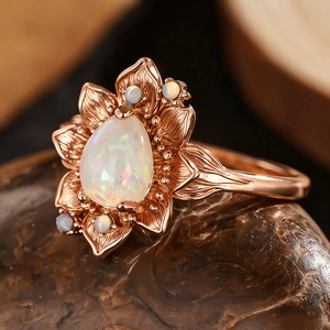 Anello girasole in oro rosa con opale a goccia d'acqua su sfondo di pietra naturale